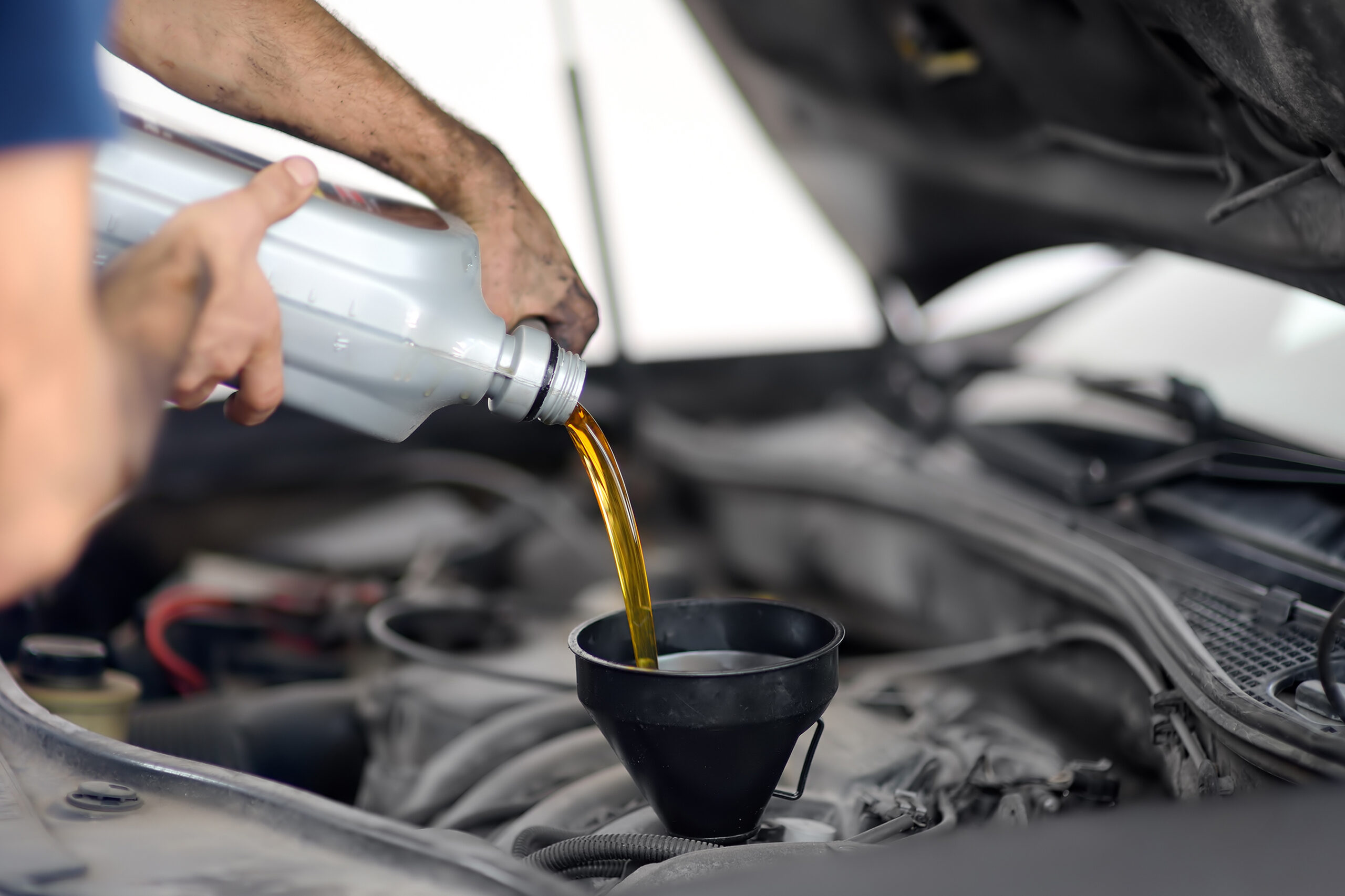 Man auto mechanic repairs car in autoservice, station. Changes oil